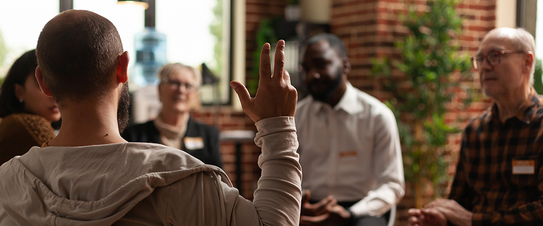 yolo-1080x450-118 man raising his hand in a group therapy session